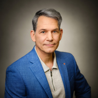 Dr Urban Pappi Portrait eines grauhaarigen Herrn in hellblauem Jackett und beigefarbenem Polohemd.