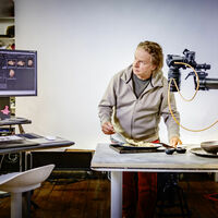 Ein Mann fotografiert einen Teller mit einem Bohnengericht und kontrolliert das Ergebnis auf zwei Bildschirmen.
