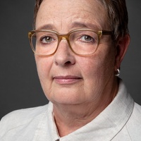 Dr. Anke Schierholz Portrait einer Frau mit Brille und beigefarbener Leinenbluse.